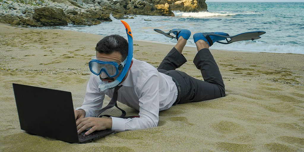 hombre en la playa con computadora