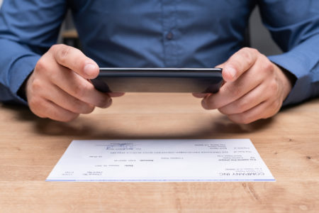 hombre toma la foto del cheque de pago con el teléfono celular