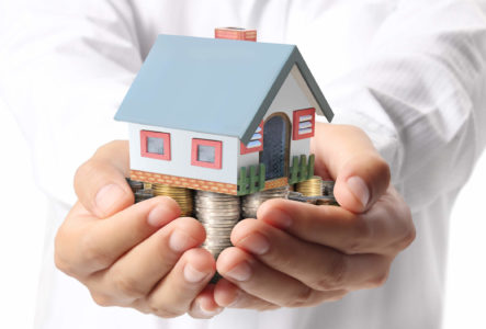 man holding small house on pile of money saved from tax tips for homeowners