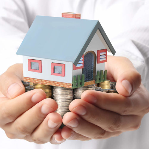 man holding small house on pile of money saved from tax tips for homeowners